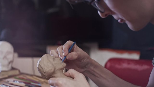 Young artist sculpting bust of woman with Plasticine (non-drying clay)