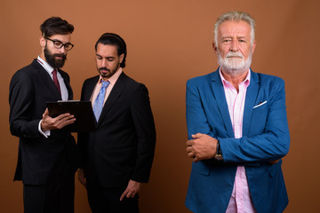 Three multi ethnic bearded businessmen together against brown background