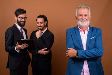 Three multi ethnic bearded businessmen together against brown background