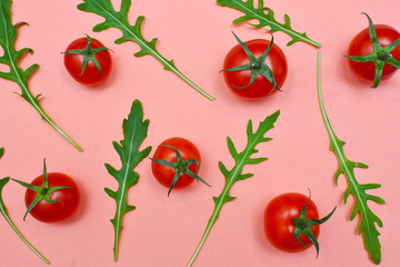Set of red fresh cherry tomatoes and arugula leaves on red background