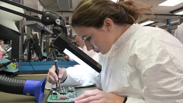 Young woman apprentice working in microelectronics lab