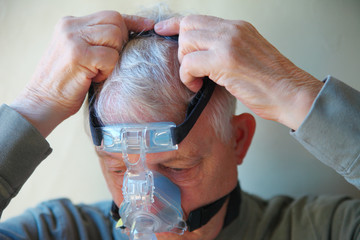 Older man puts on CPAP device head gear