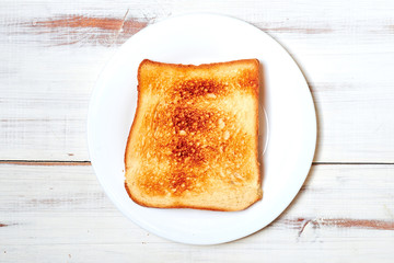 Toasted toast on a plate on a light wooden background.