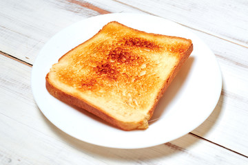 Toasted toast on a plate on a light wooden background.