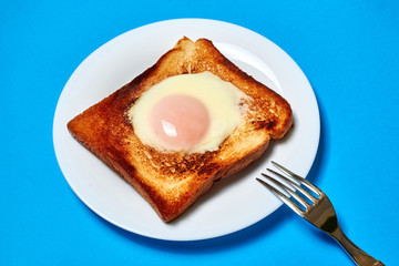 Toast with an egg on a plate on a blue background.