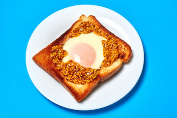 Toast with an egg on a plate on a blue background.