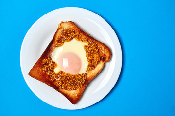 Toast with an egg on a plate on a blue background.