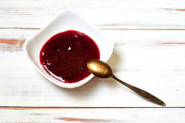 Strawberry jam on a light wooden background.