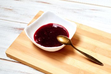 Strawberry jam on a light wooden background.