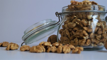 peeled walnut kernels in a glass jar for storing food on a light background