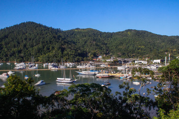 Fototapeta na wymiar many boats and yachts anchored in a cozy bay among the lush tropical vegetation against the backdrop of the mountains. Rich luxury yachts in the bay
