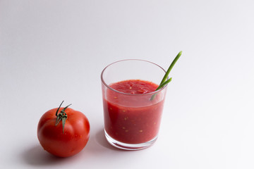 glass of natural fresh  tomato juice with green onion strow, ripe tomato on white background