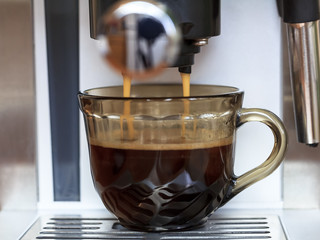 Pouring coffee from a coffee machine into a cup