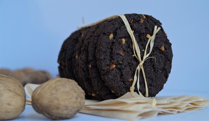 brownie cookies tied with ribbon, behind whole walnuts on a light background