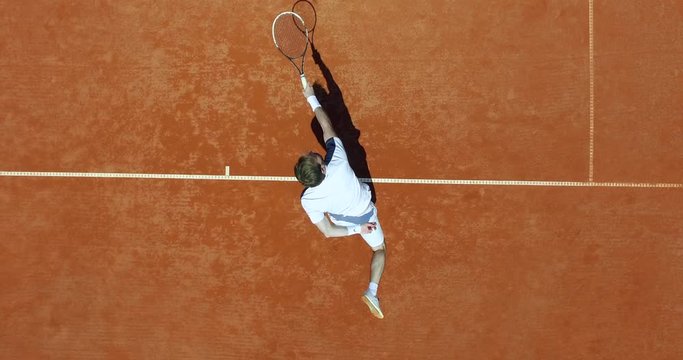 Tennis player hitting the ball on the red court. Summer sport concept. Top aerial view footage. 