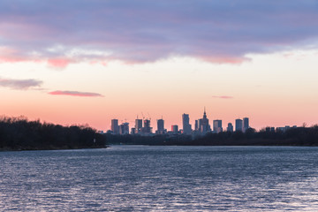 Warsaw skyline with skyscrapers during colorful sunset over the Vistula River.