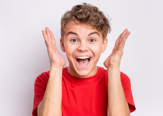 Portrait of surprised teen boy, on grey background. Funny child looking at camera in shock or...