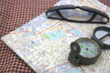 Paper map and a classic compass next to sunglasses
