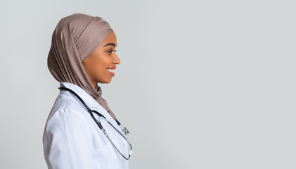 Afro muslim female doctor in hijab and lab coat, profile portrait