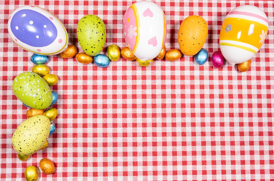 Mix of easter eggs of all colors and sizes on a background of red and white gingham fabric. Easter concept