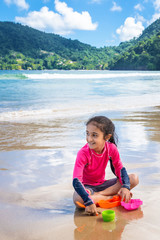 Little girl playing with sand on Maracas Bay Beach Trinidad