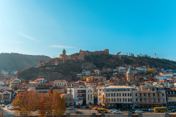 Fototapeta na wymiar Tbilisi, Georgia, 17 December 2019 - city view with colorful traditional houses with wooden carved balconies, Narikala fortress, Mother Georgia monument and cable road in the Old Town