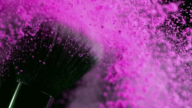Super slow motion of makeup brush with falling powder, black background. Filmed on high speed cinema camera, 1000fps.