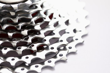 Close-up of metal gearwheel on light background. Detail from bicycle pedal. Device, consisting of connected sets of wheels with teeth around the edge. Mechanism and engineering concept