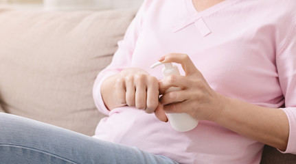 Mature woman moisturizing hand skin with lotion