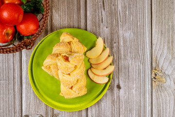 Apple strudel with fresh red apples on wooden table.