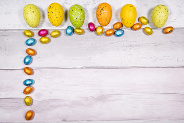 Mixtures of easter eggs of all colors and sizes on a background of old wooden boards resembling old parquet. Easter concept