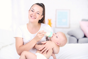 Obraz na płótnie Canvas Young mother feeding her baby son at home