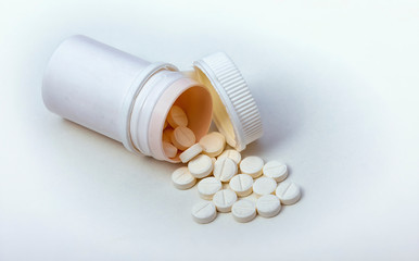 Pills from a jar on a white background