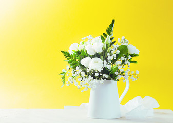 Flowers in a vase on marble table and yellow background with  space for text.