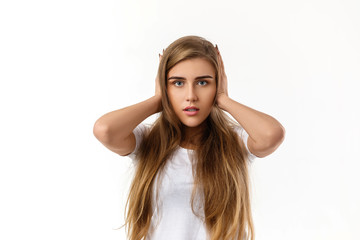 Fototapeta premium Portrait of young beautiful woman closes her ears with hand on white background