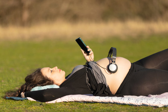 Pregnant woman with headphones over her belly