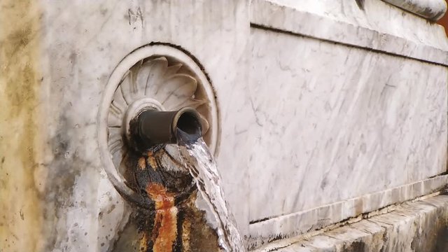 Slow motion running water out of a marble fountain in Italy