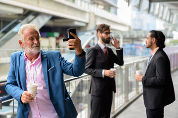 Three multi ethnic bearded businessmen together around the city