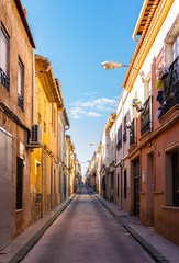 A long straight and narrow street lined by colorful houses in Aspe town centre.