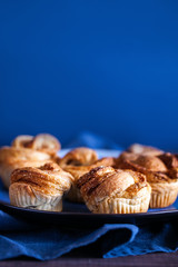 Trendy modern pastries.Fresh baked cruffins (Croissant and Muffin) with cinnamon and brown sugar on blue background with copy space for text.Vertical orientation
