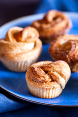 Trendy modern pastries.Fresh baked cruffins (Croissant and Muffin) with cinnamon and brown sugar on blue background close-up.Vertical orientation