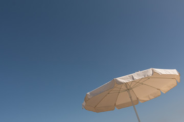Fototapeta na wymiar Big white parasol in front of a sunny blue sky