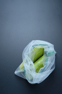 Composition with zucchini in a string bag on a black background. Zero waste.