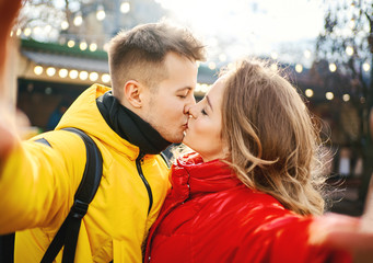 Fototapeta premium young romantic couple in love making selfie, kissing to to the camera. Spending time together in the city, having a date. urban romantic portrait. Romantic, love and Valentine's Day concept.