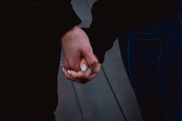 Couple of people is holding the hands in a winter wooden bridge