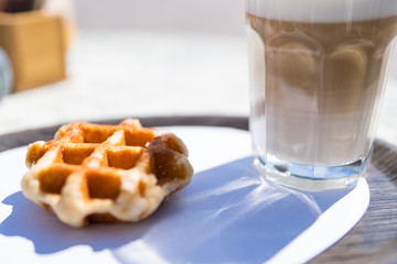 close up Brussels Waffle with glass of Latte Macchiato on terrace table
