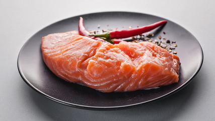 Food banner. Fresh salmon slice, herbs, spices and hot peppers on a dark plate.