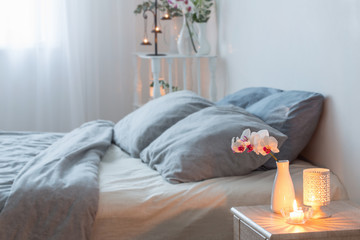orched flowers  in vase and burning candles in white bedroom