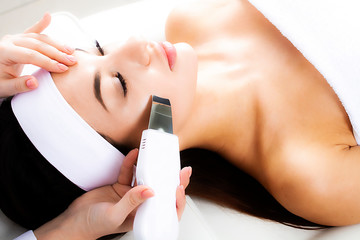 Ultrasound face therapy close-up. The cosmetologist makes the patient a face cleaning with an ultrasound apparatus in a cosmetology clinic.