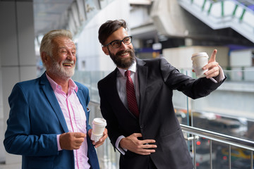 Two multi ethnic bearded businessmen together around the city